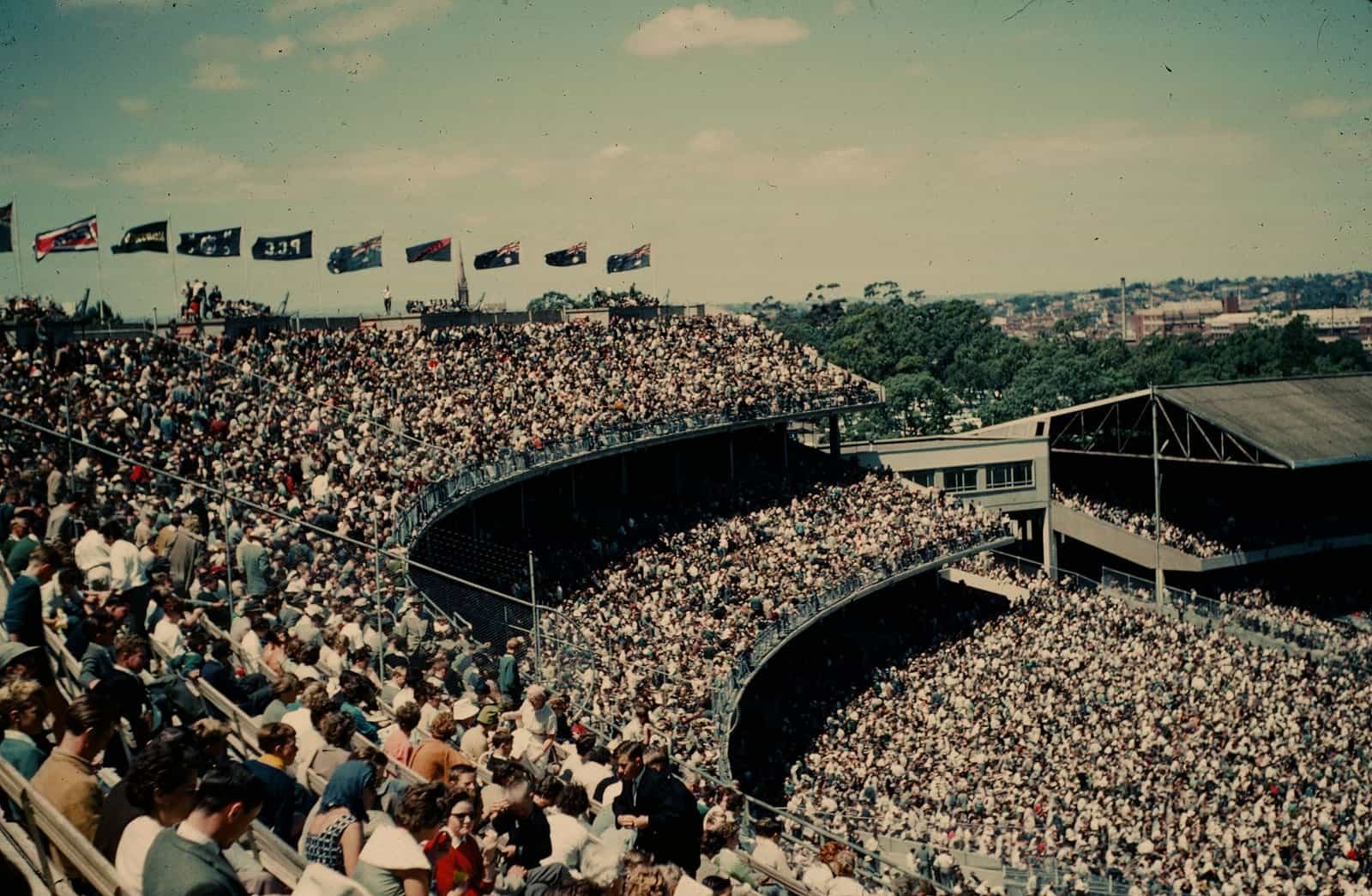 A packed crowd in the stands at the Melbourne Cricket Ground, flags flying above the terraces