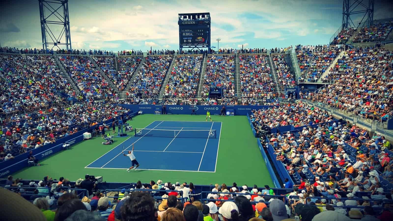 A packed stadium court at the US Open, Flushing Meadows, showing the blue hard court inside its green surround